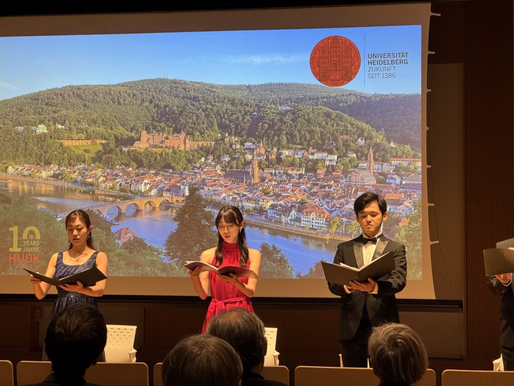 Musicians in front of a picture of Heidelberg city.